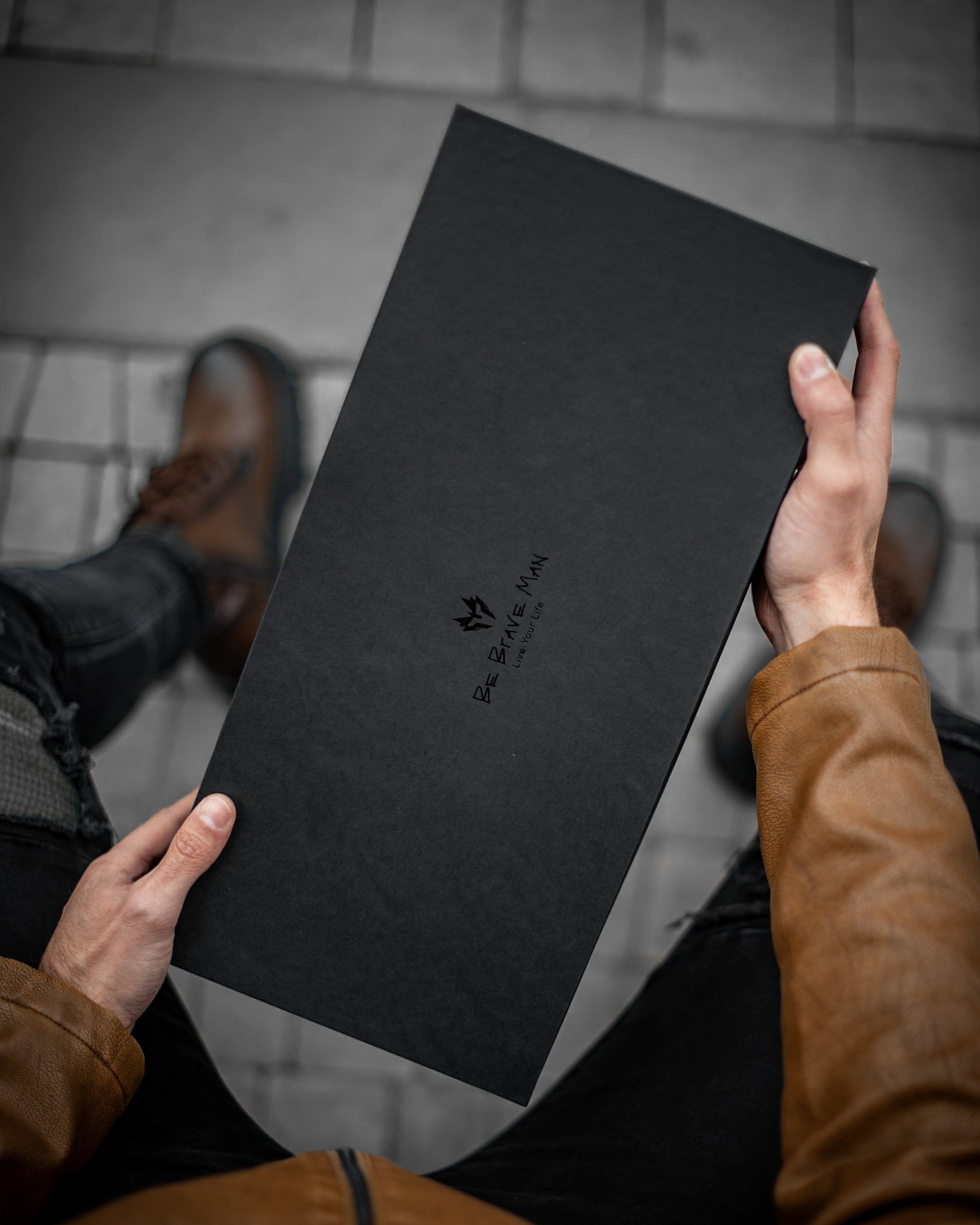 Muška kožna torba Toro - Crna Boja - Muškarac drži u rukama kutiju za torbu i pokazuje prednju stranu