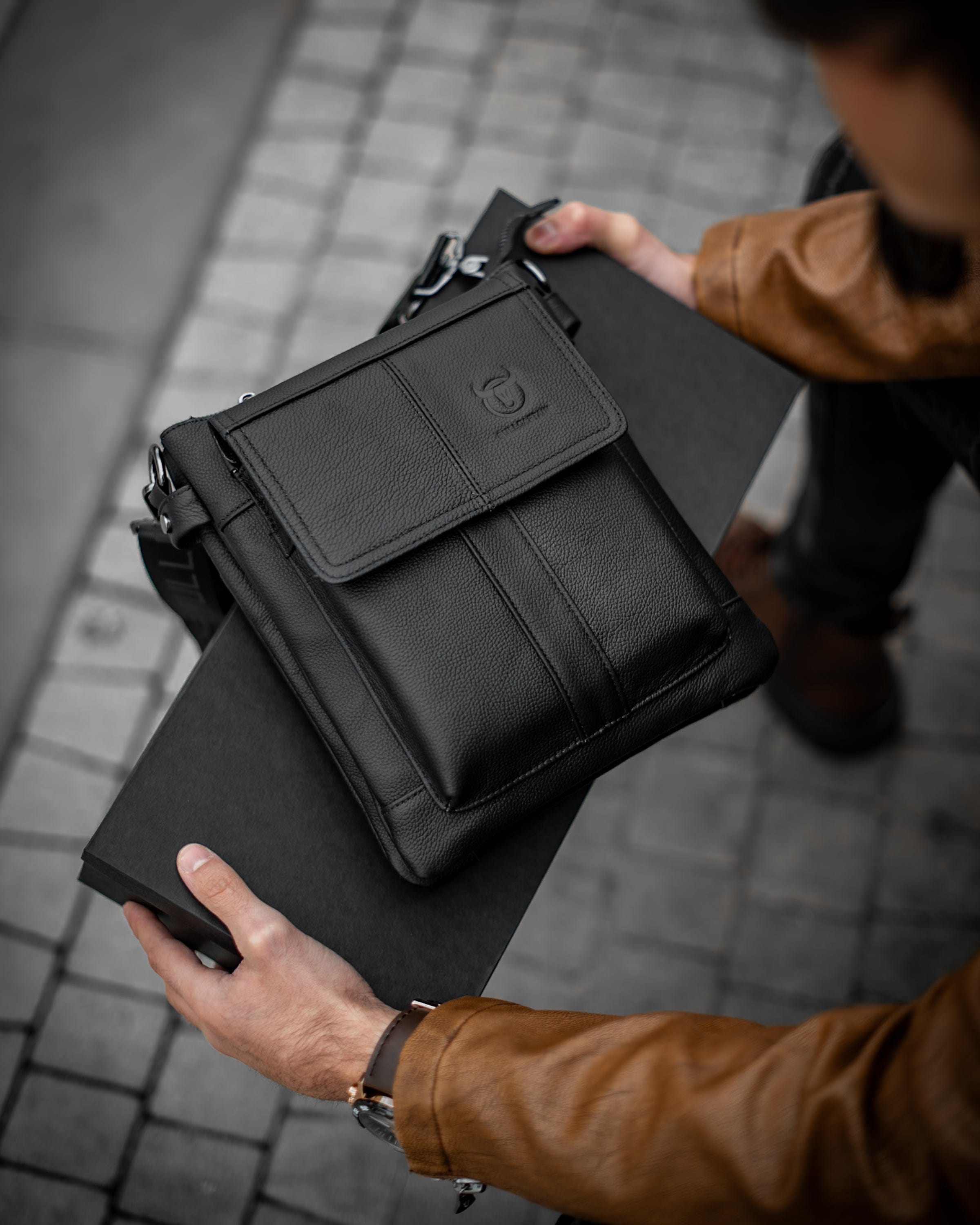 Muška kožna torba Toro - Crna Boja - Muškarac drži u rukama torbu i pokazuje prednju stranu