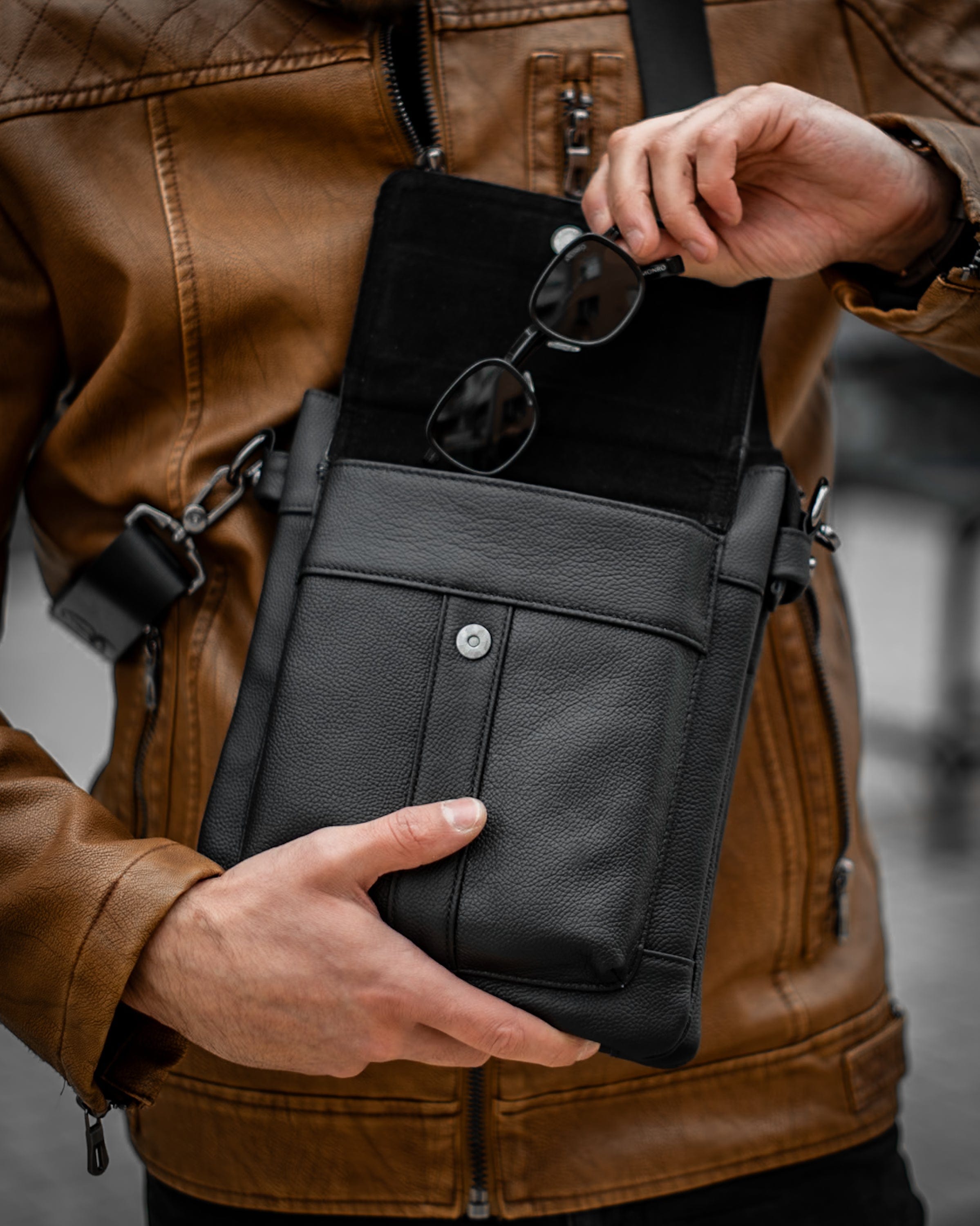Muška kožna torba Toro - Crna Boja - Muškarac drži u rukama torbu i pokazuje otvorenu pregradu