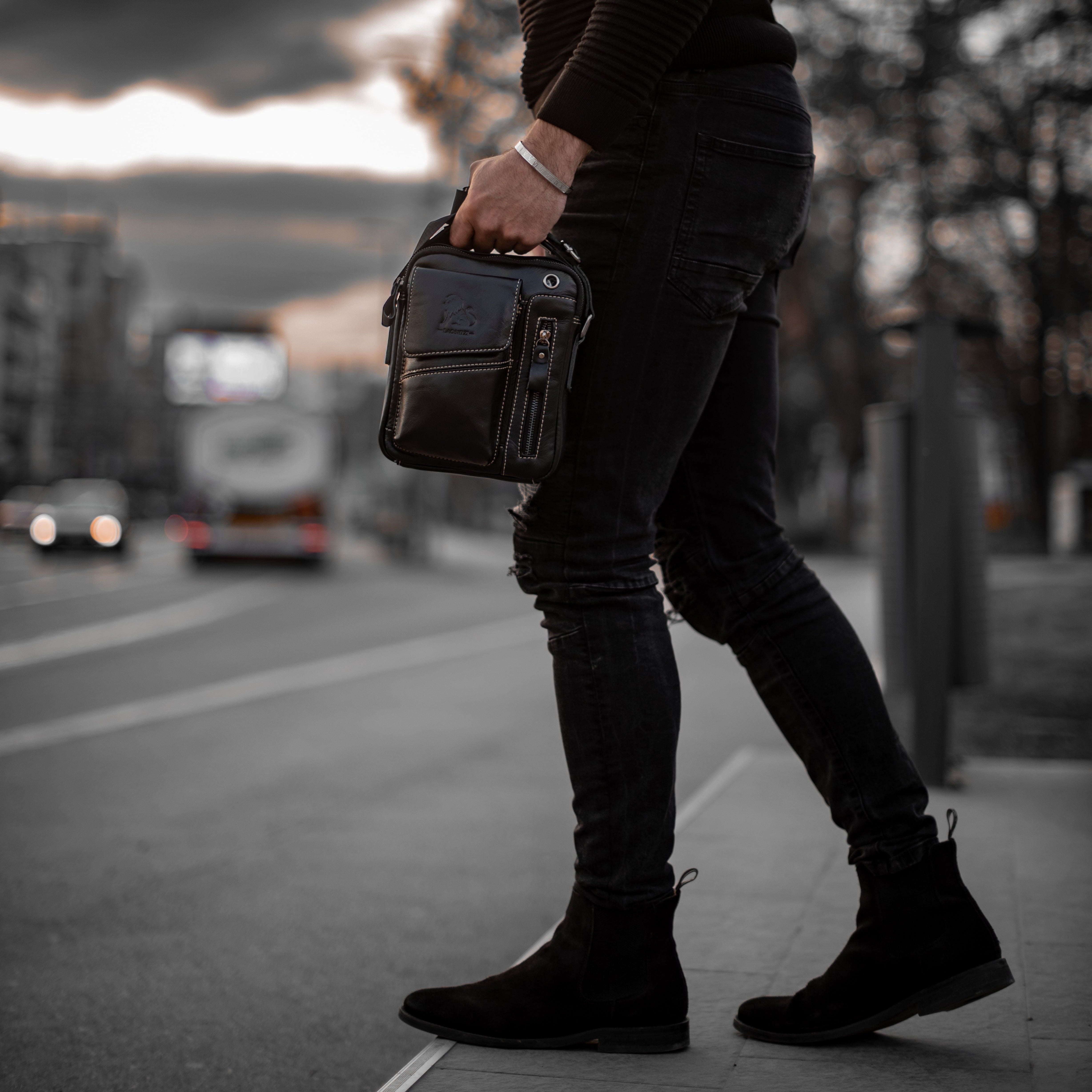 Muška Kožna Torba Leo - Crna Boja - Muskarac drzi u ruci torbu i pokazuje prednju stranu