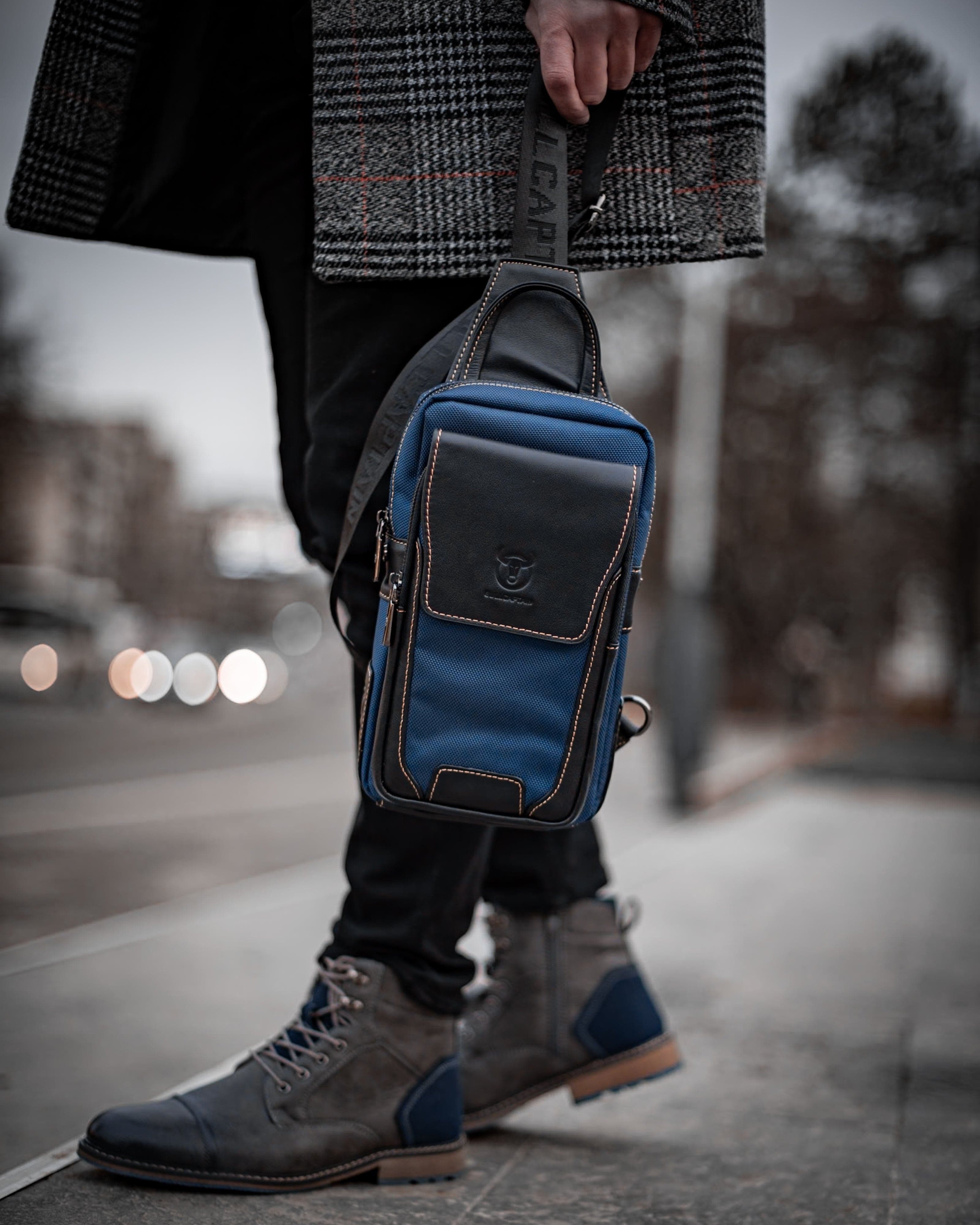 Muška Kožna Torba West - Plava Boja - Muskarac drzi u ruci kaiš torbe i pokazuje prednju stranu