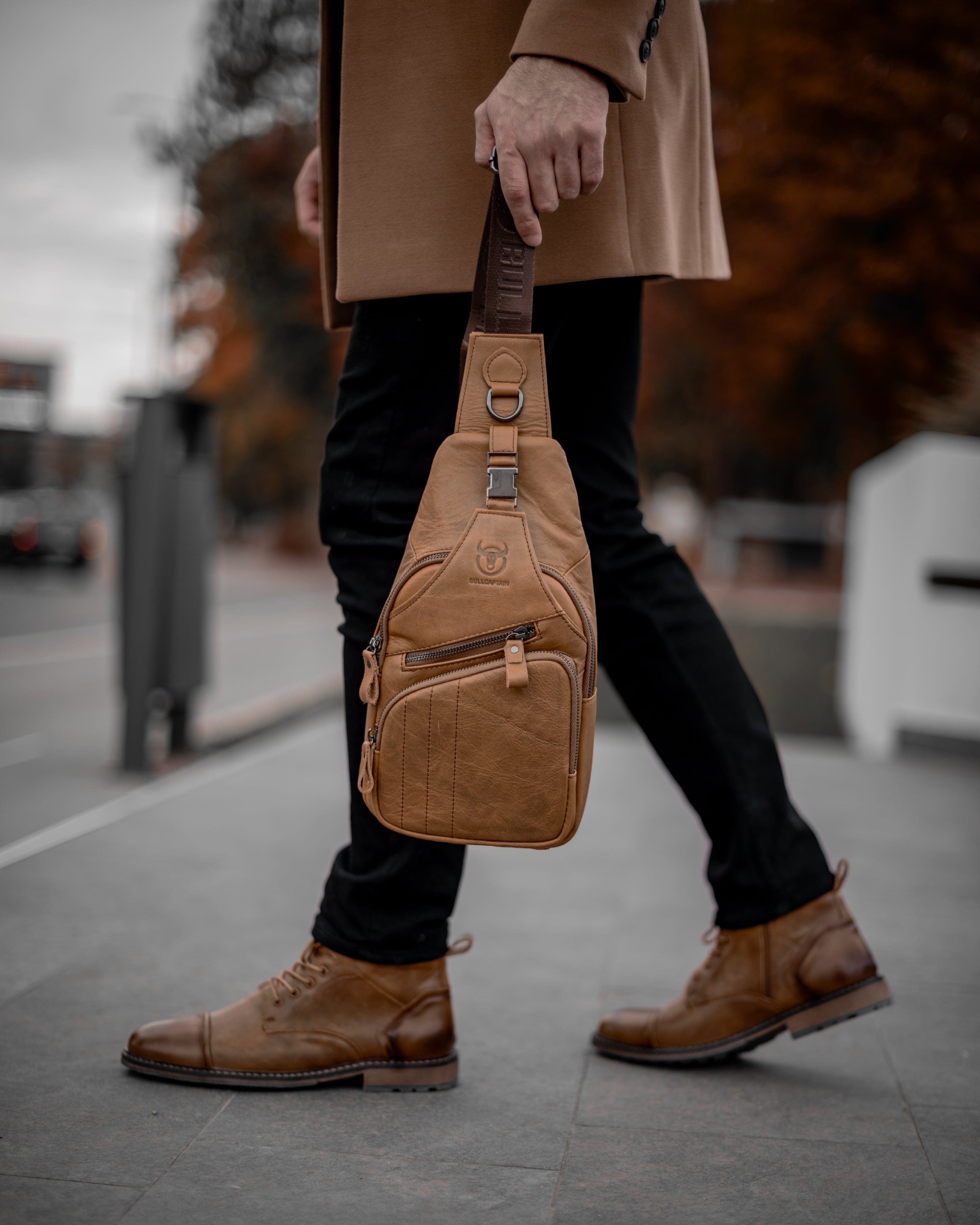 Muška Kožna Torba Tour - Svetla Braon Boja - Muskarac drzi u ruci kaiš torbe i pokazuje prednju stranu