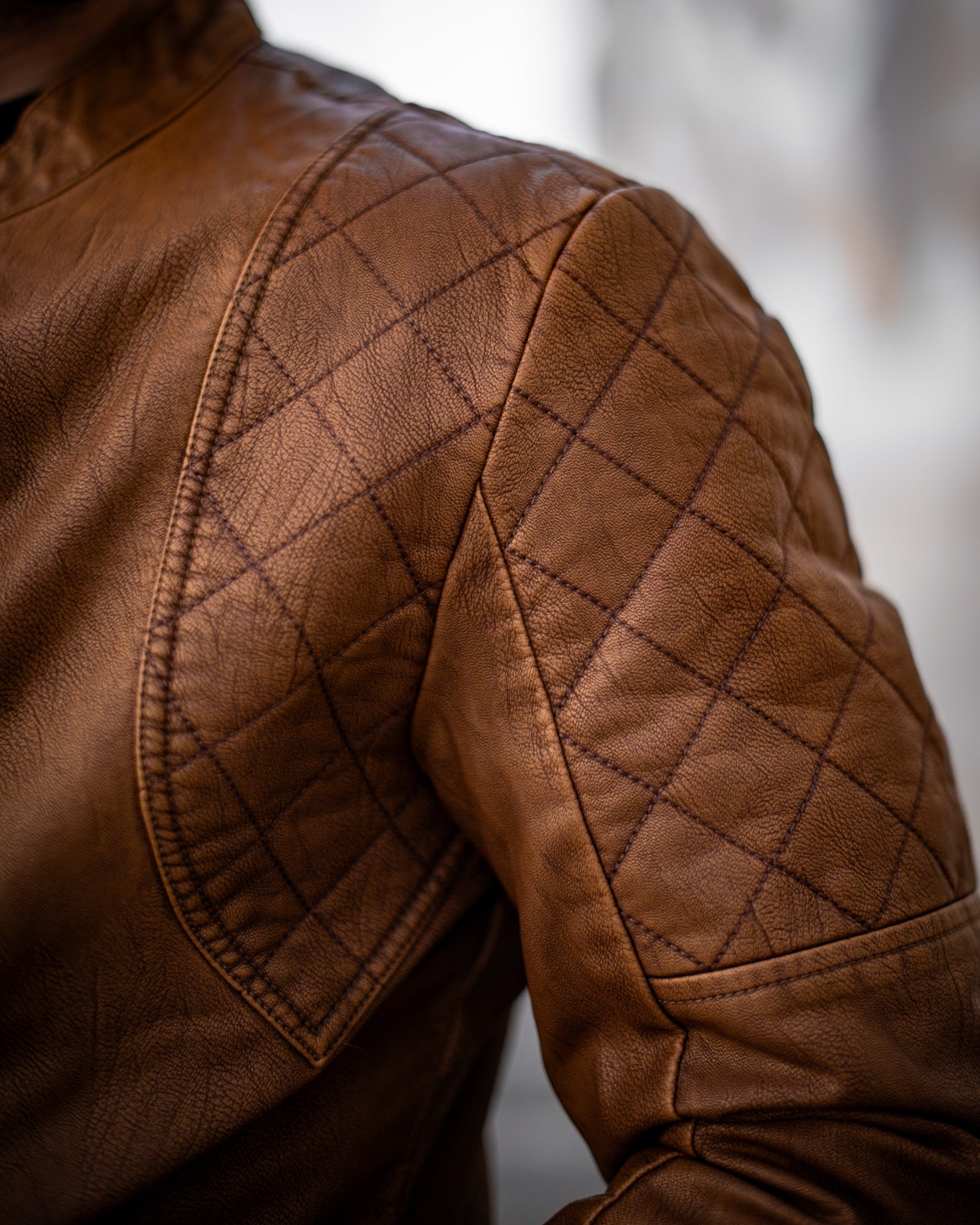 Muskrac nosi musku koznu letnju jaknu u braon boji i prikazuje izbliza detalje na ramenu jakne. Najbolja cena i prodaja u Srbiji. Model 3