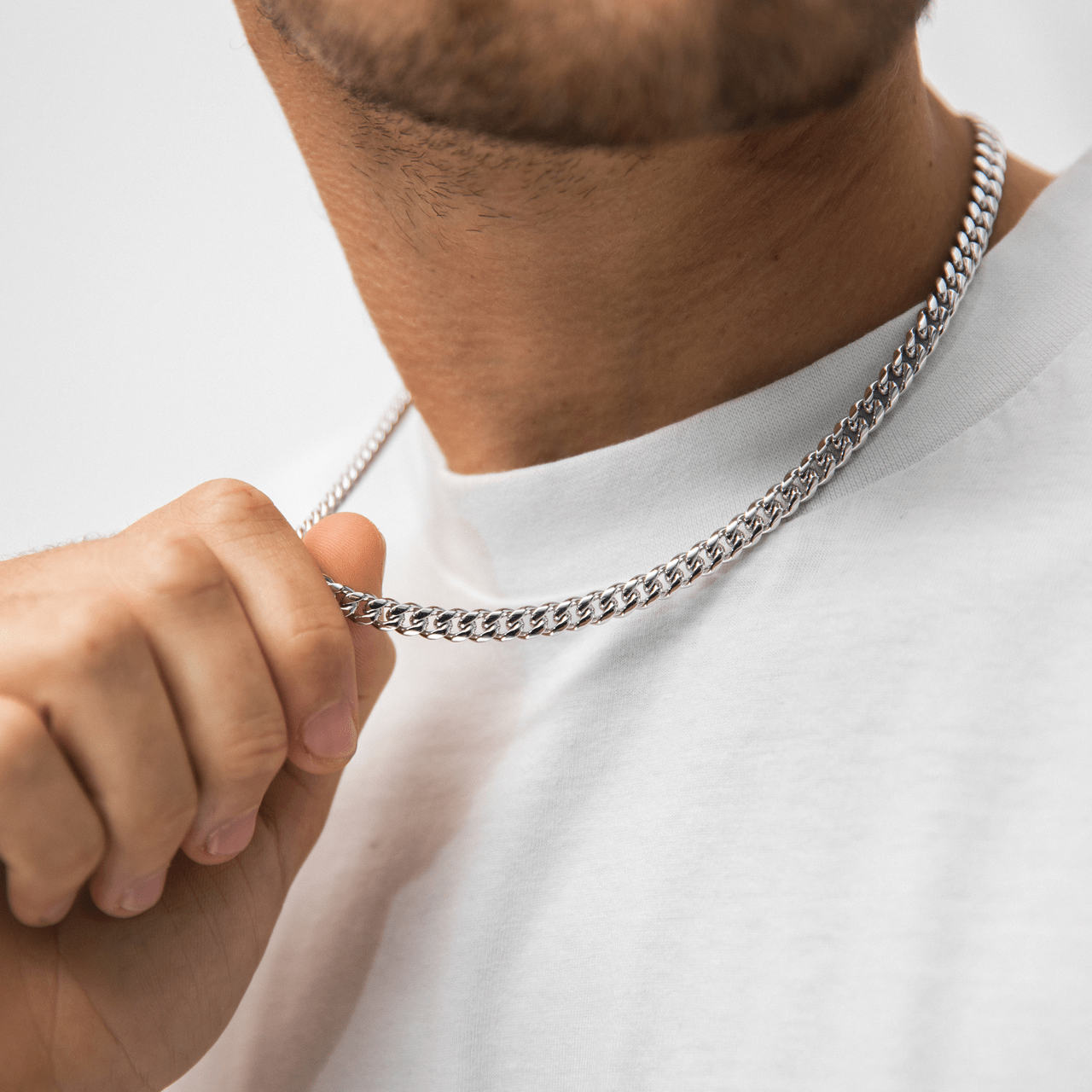 Muskarac nosi oko vrata i rukom prikazuje musku ogrlicu Cuban 7mm, lanac HIRUSKI CELIK, srebrna boja model 28