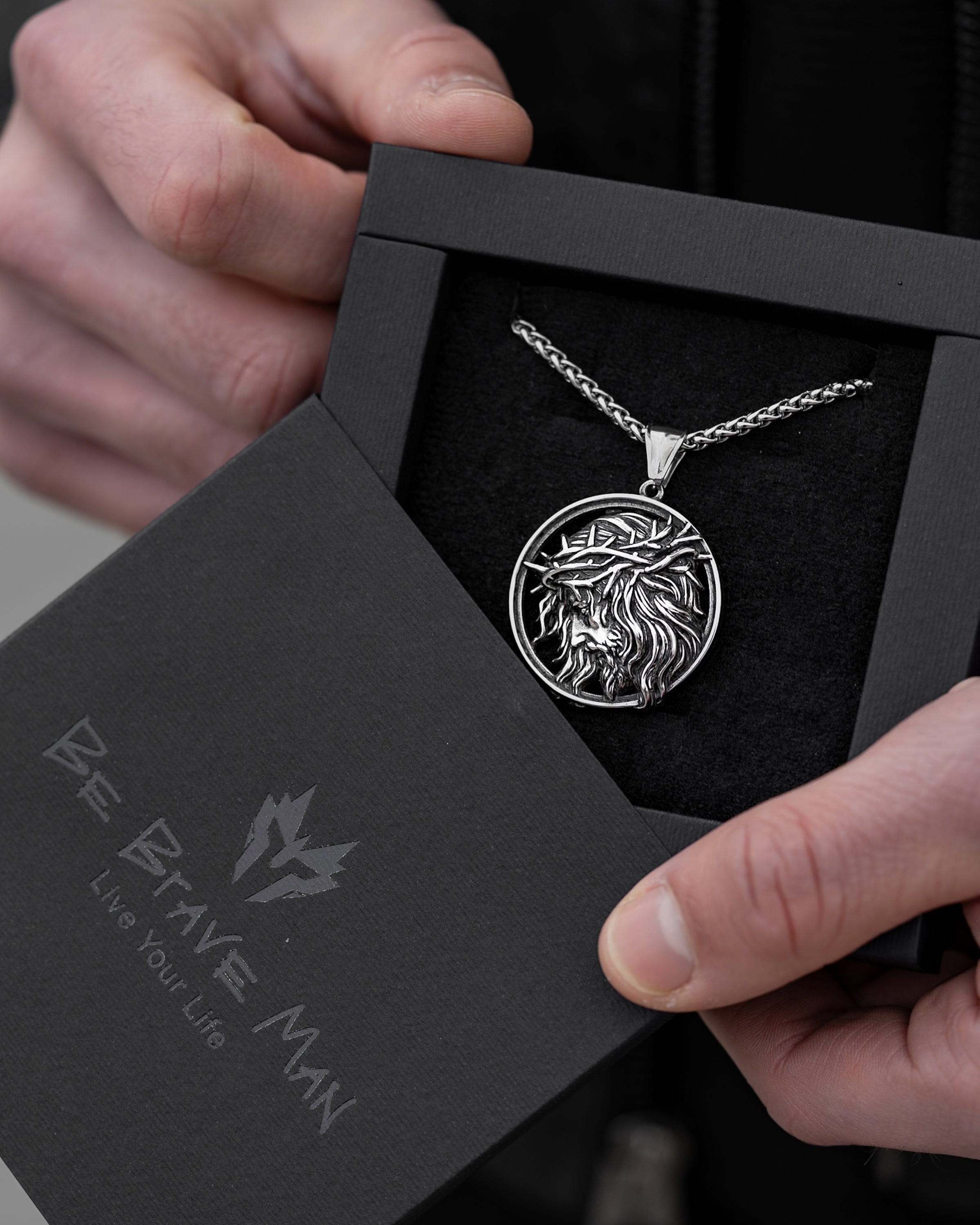 Muskarac drzi i pokazuje kutiju sa muskom ogrlicom Crown of Thorns, Privezak i lanac HIRUSKI CELIK, srebrna boja, Najbolja cena i prodaja u Srbiji, model 15