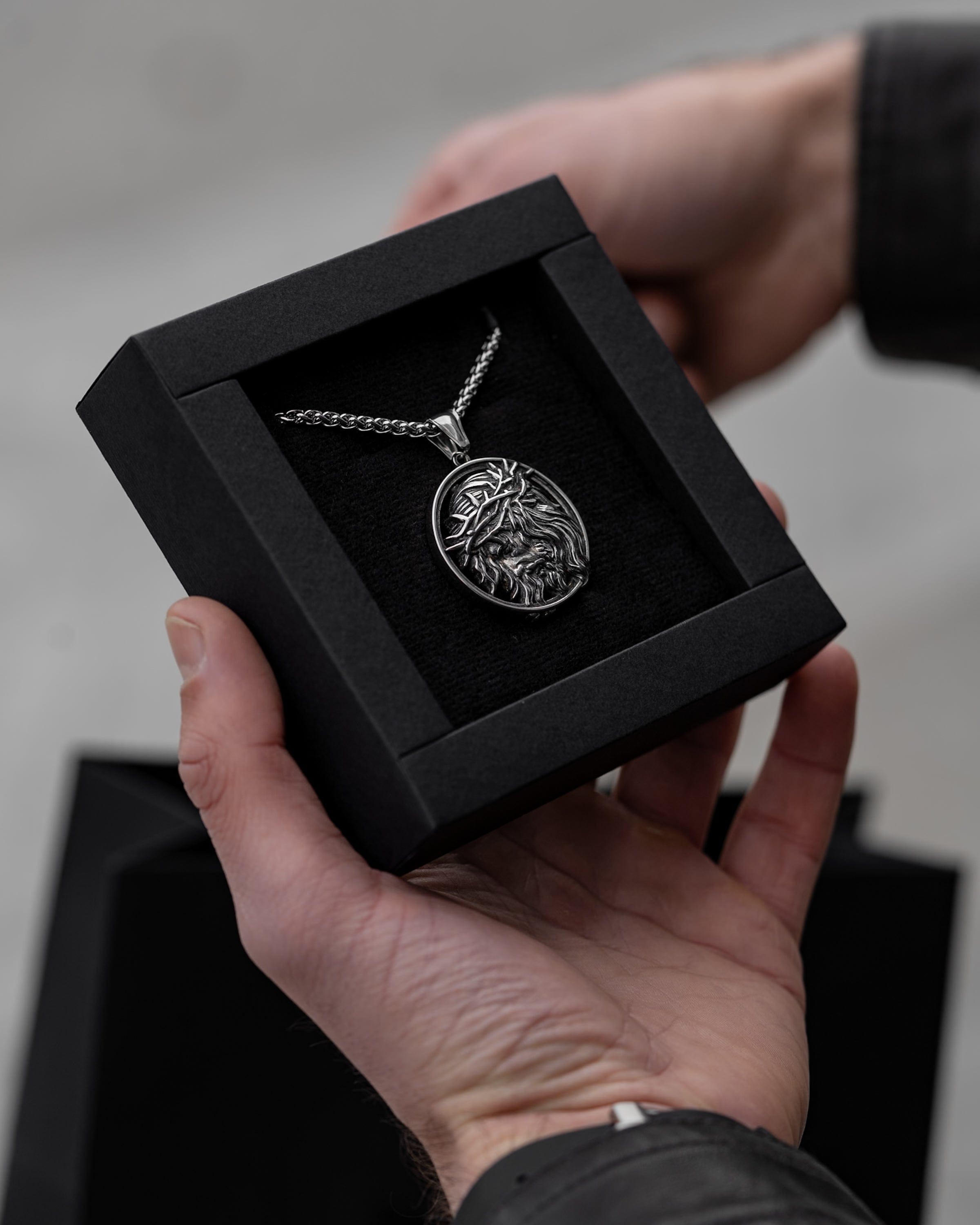 Muskarac drzi u ruci kutiju sa muskom ogrlicom Crown of Thorns, Privezak i lanac HIRUSKI CELIK, srebrna boja, Najbolja cena i prodaja u Srbiji, model 15