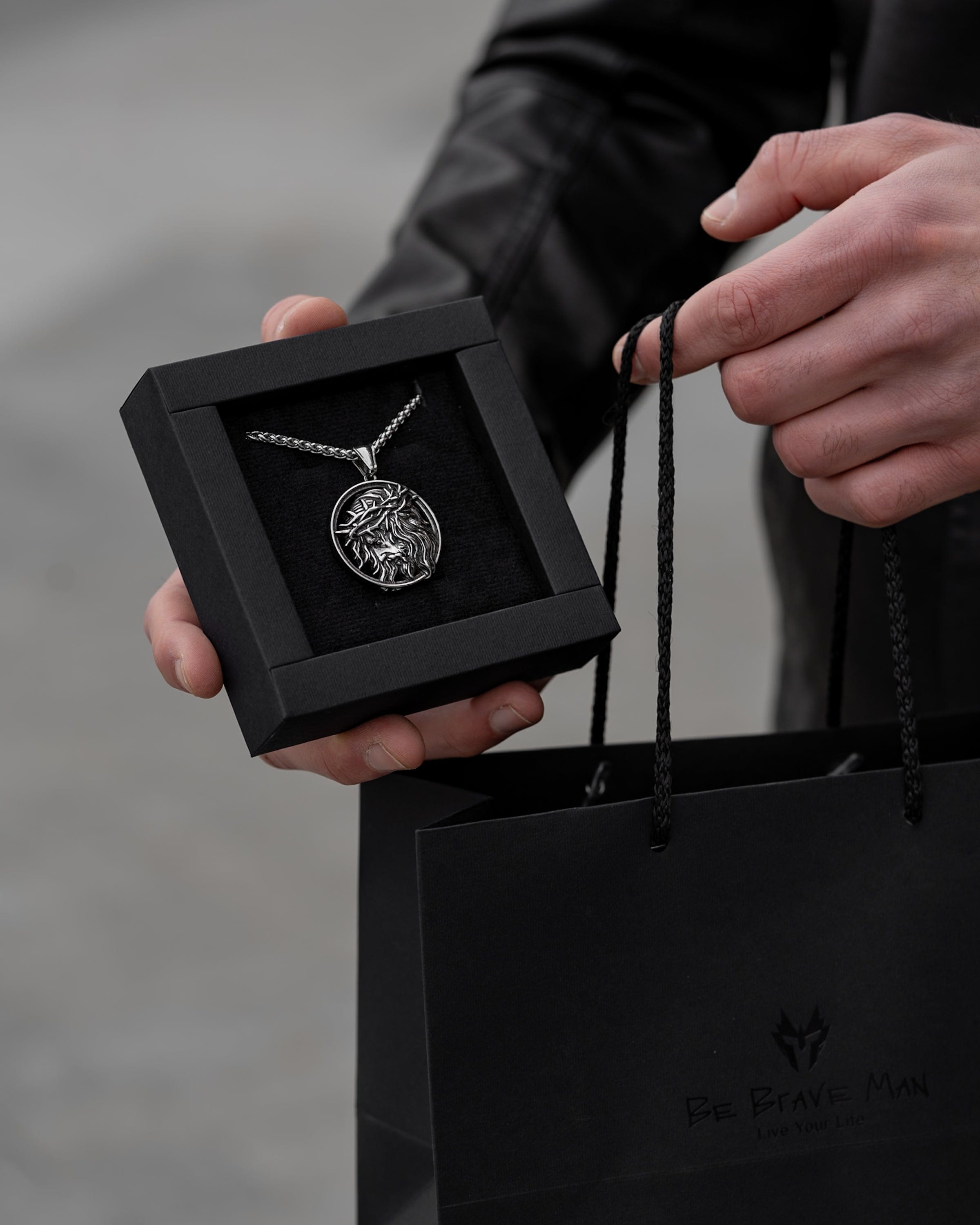 Muskarac drzi i pokazuje kutiju sa muskom ogrlicom Crown of Thorns , Privezak i lanac HIRUSKI CELIK, srebrna boja, Najbolja cena i prodaja u Srbiji, model 15