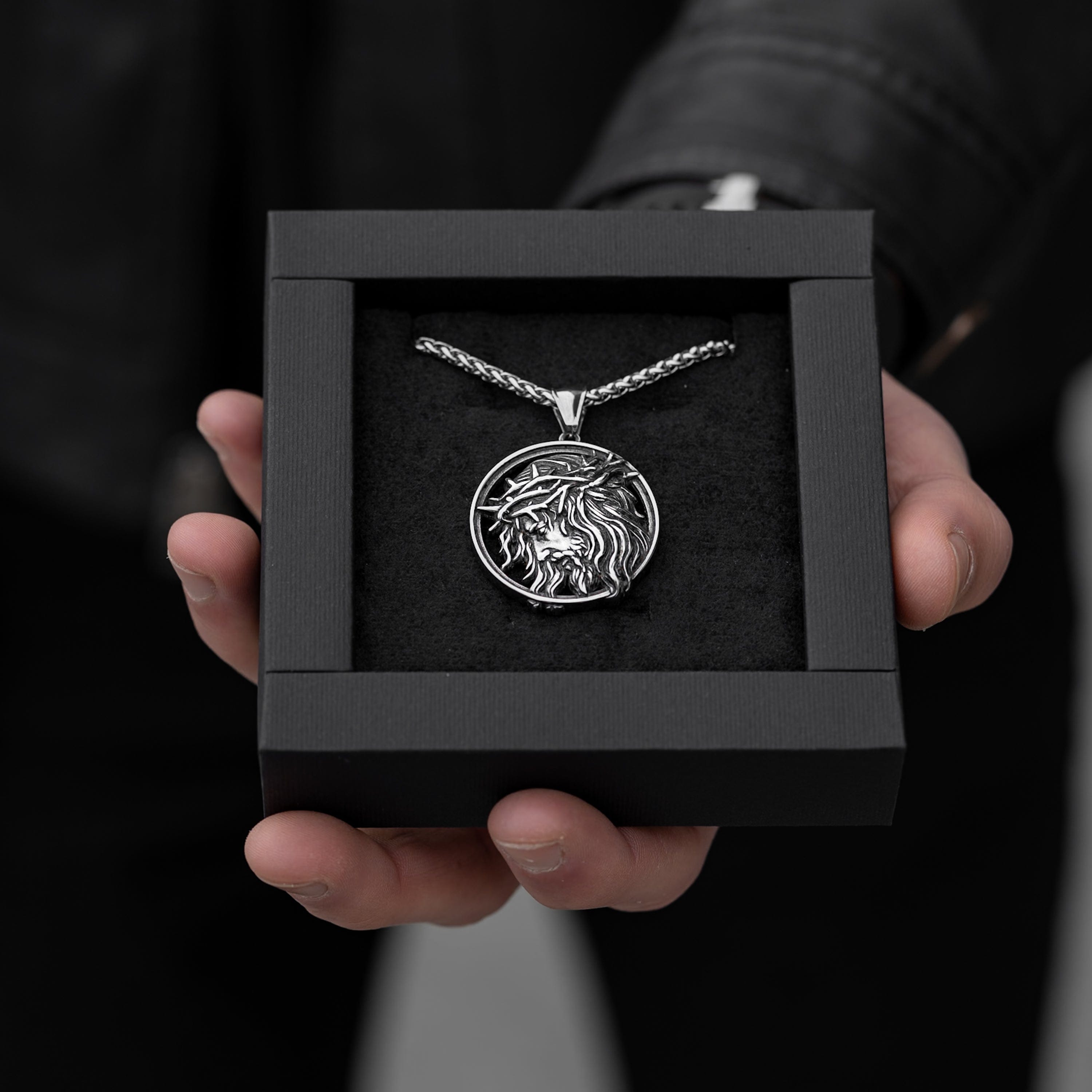 Muskarac drzi u ruci kutiju sa muskom ogrlicom Crown of Thorns , Privezak i lanac HIRUSKI CELIK, srebrna boja, Najbolja cena i prodaja u Srbiji, model 15