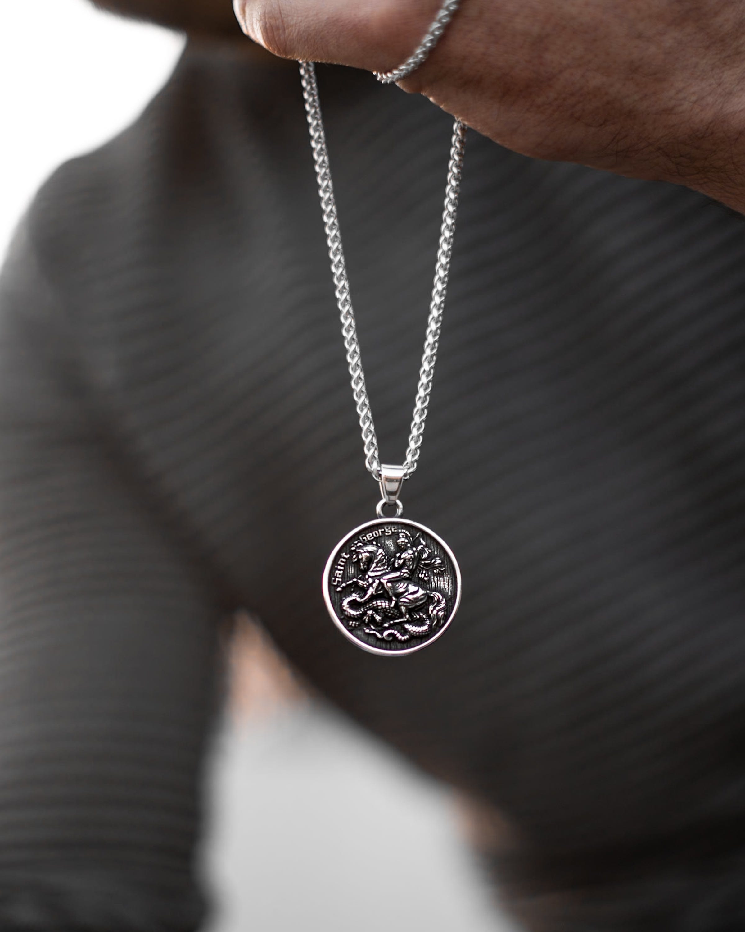 Muskarac drzi u ruci lanac muske ogrlice Saint George, Privezak i lanac HIRUSKI CELIK, srebrna boja, Najbolja cena i prodaja u Srbiji, model 20