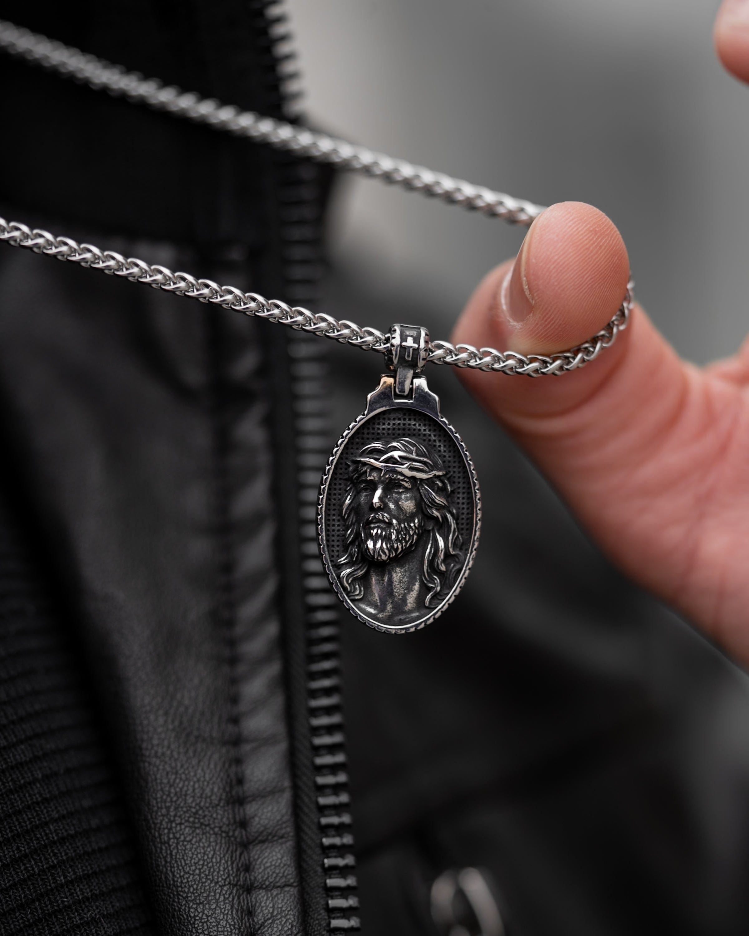 Muskarac pokazuje gravuru priveska muske ogrlice Jesus of Nazareth, Privezak i lanac HIRUSKI CELIK, srebrna boja, Najbolja cena i prodaja u Srbiji, model 25