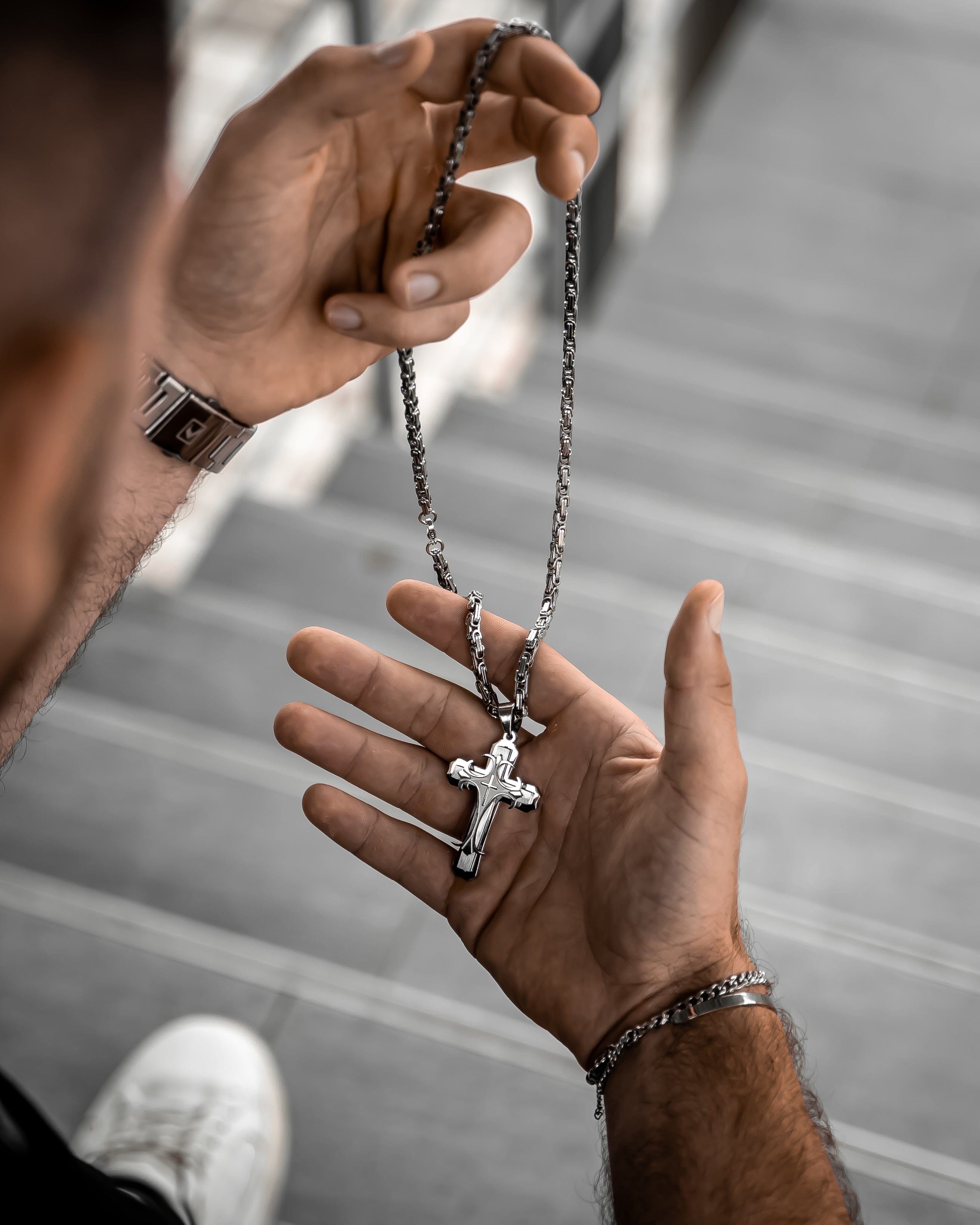 Muskarac drzi u ruci i detaljno pokazuje privezak muske ogrlice Iron Cross, Privezak i lanac HIRUSKI CELIK, srebrna boja, Najbolja cena i prodaja u Srbiji, model 23