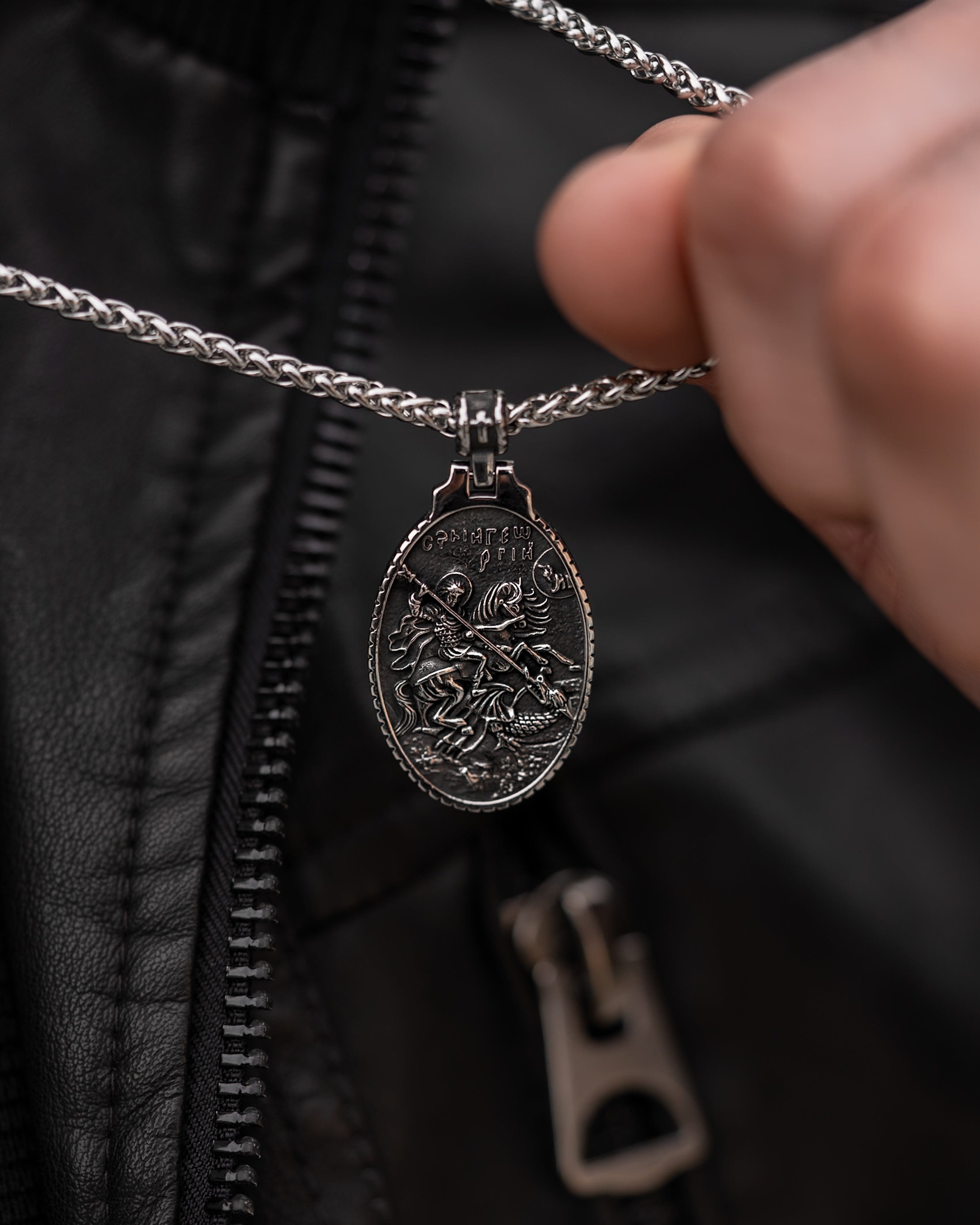 Muskarac rukom drzi lanac i prikazuje privezak muske ogrlice SV. Georgije Silver, Privezak i lanac HIRUSKI CELIK, srebrna boja, Najbolja cena i prodaja u Srbiji, model 25