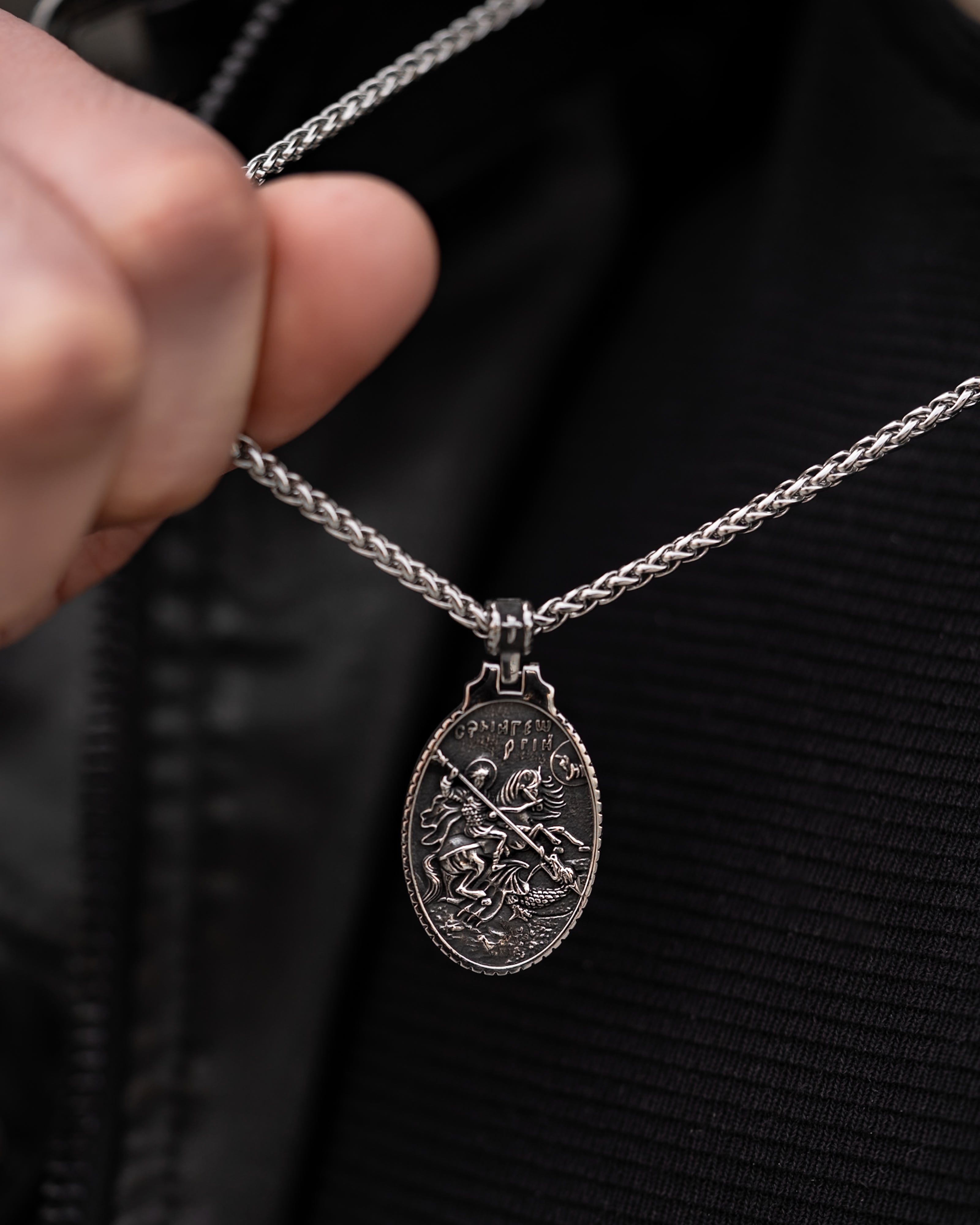 Muskarac drzi lanac i prikazuje privezak muske ogrlice SV. Georgije Silver, Privezak i lanac HIRUSKI CELIK, srebrna boja, Najbolja cena i prodaja u Srbiji, model 25