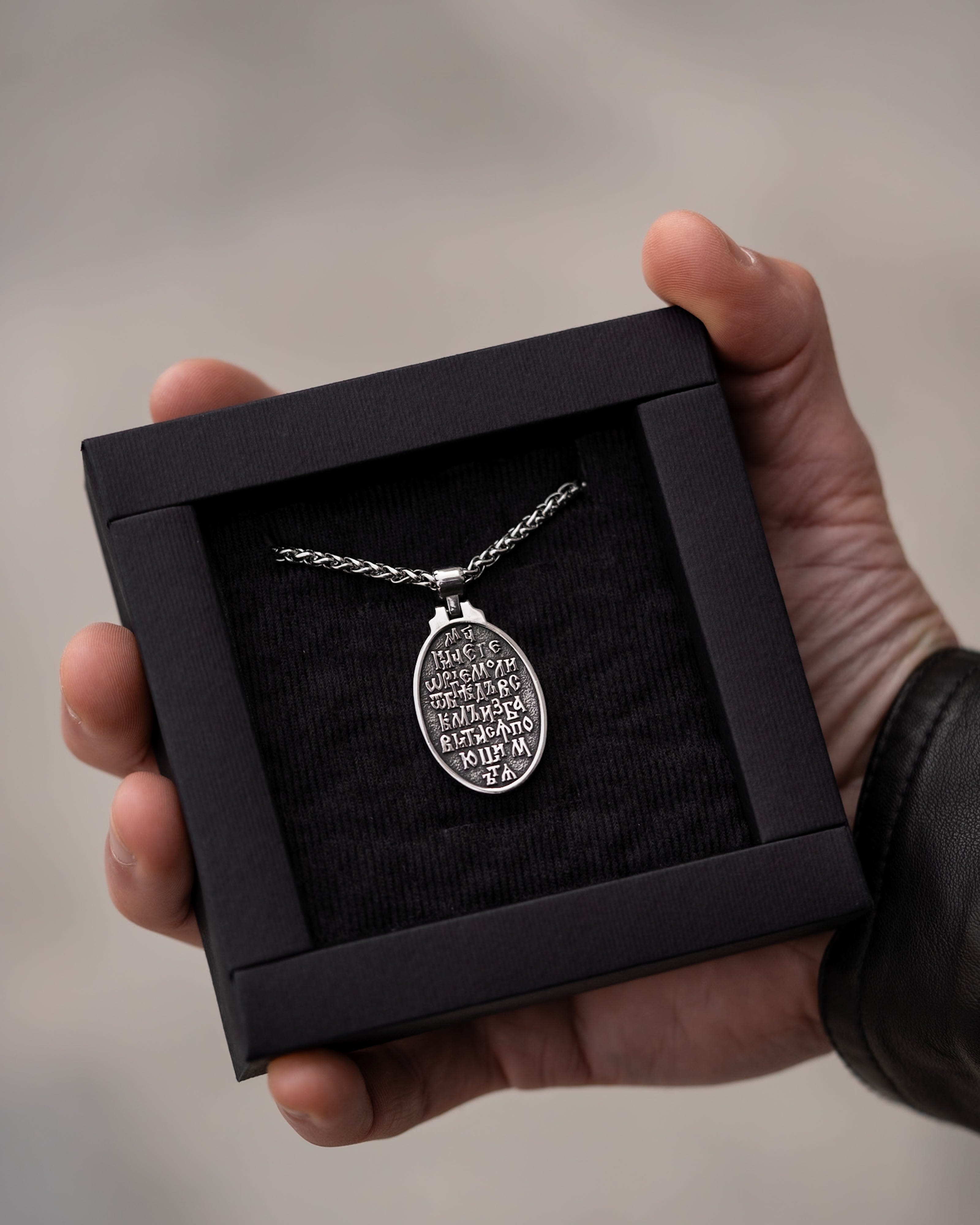 Muskarac pokazuje zadnju stranu priveska muske ogrlice SV. Georgije Silver u kutiju, Privezak i lanac HIRUSKI CELIK, srebrna boja, Najbolja cena i prodaja u Srbiji, model 25