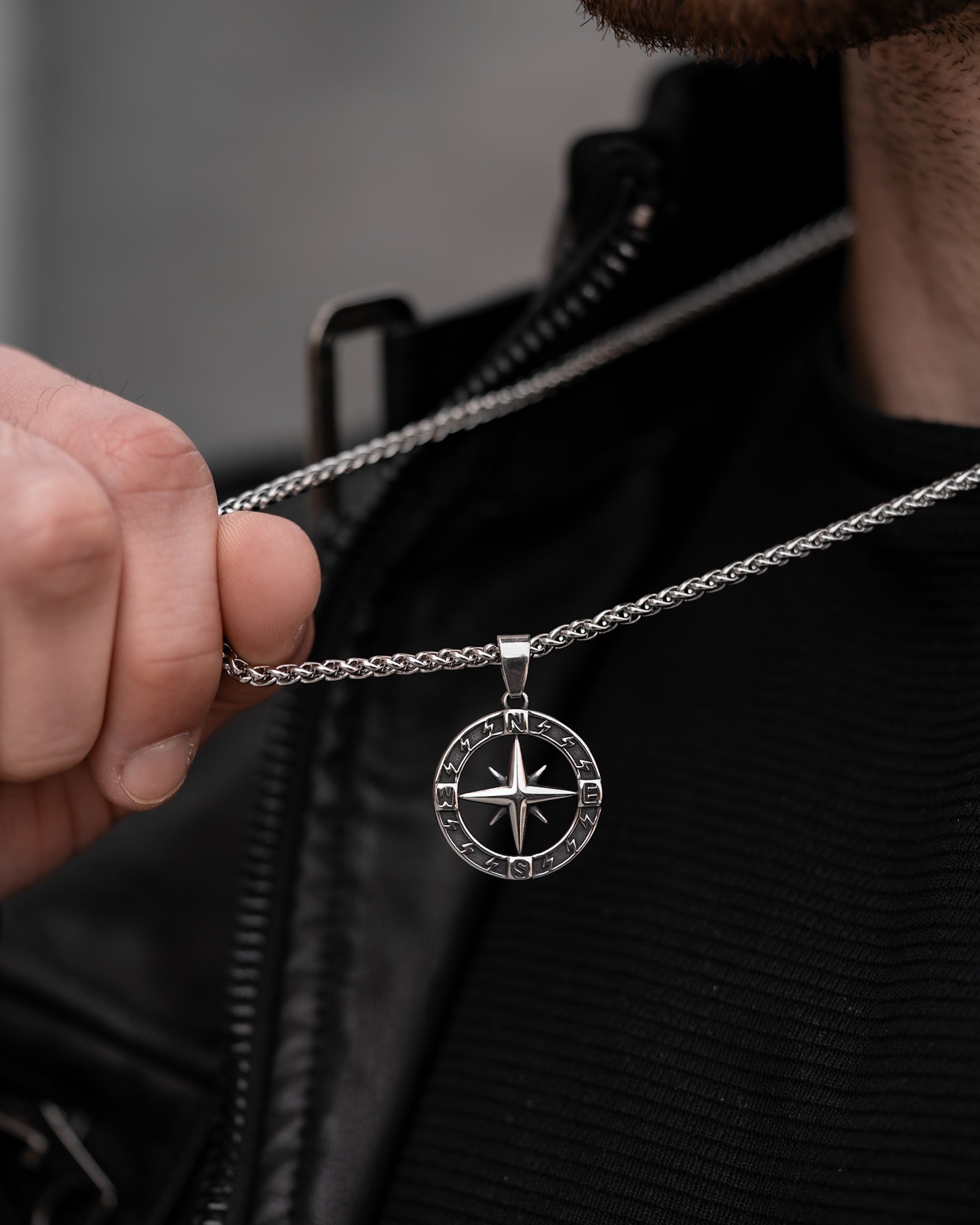 Muskarac drzi lanac i pokazuje privezak muske ogrlice Stellar North. Privezak i lanac HIRUSKI CELIK, srebrna boja, Najbolja cena i prodaja u Srbiji, model 27