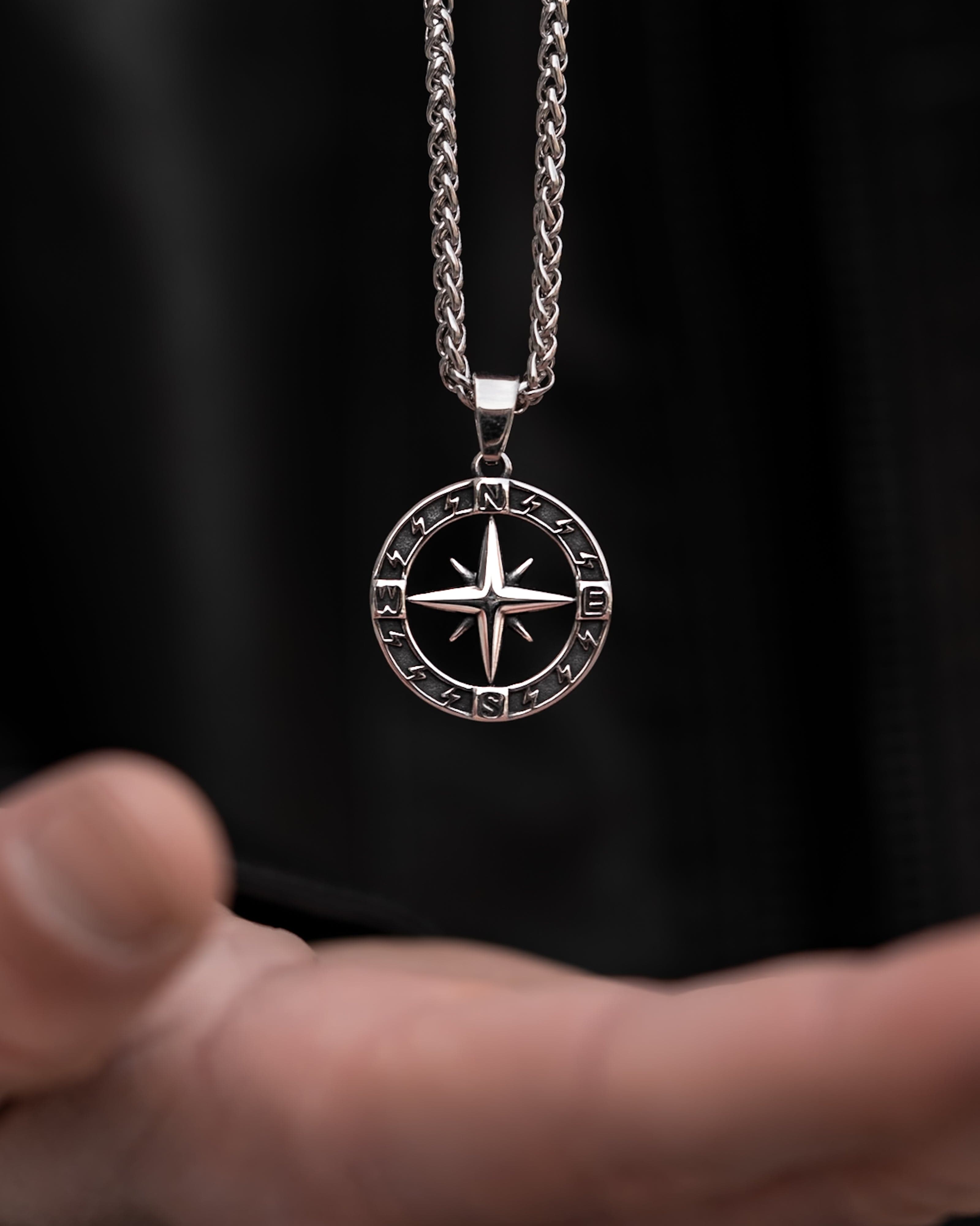 Muskarac drzi u ruci musku ogrlicu Stellar North. Privezak i lanac HIRUSKI CELIK, srebrna boja, Najbolja cena i prodaja u Srbiji, model 27