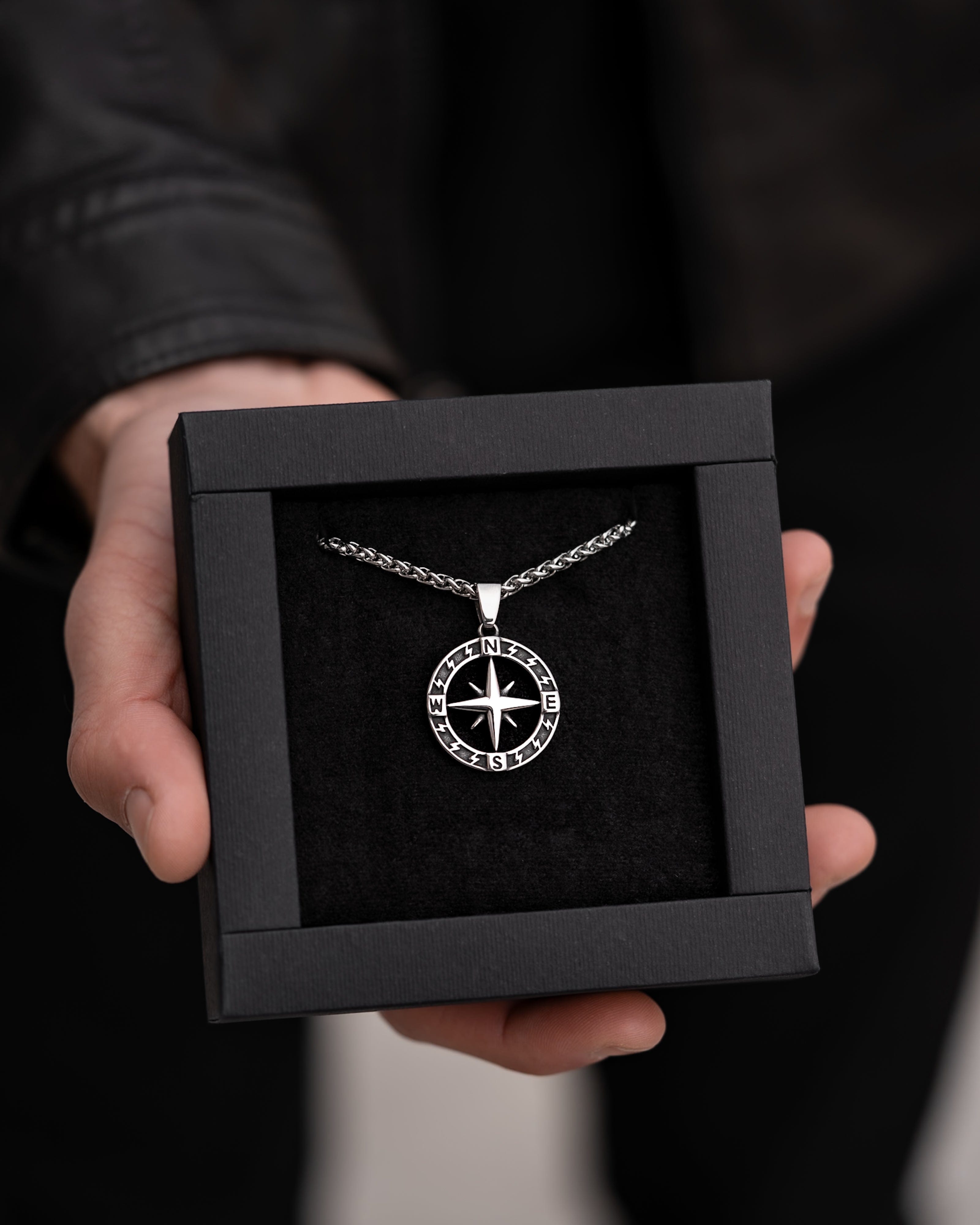 Muskarac pokazuje kutiju sa muskom ogrlicom Stellar North. Privezak i lanac HIRUSKI CELIK, srebrna boja, Najbolja cena i prodaja u Srbiji, model 27