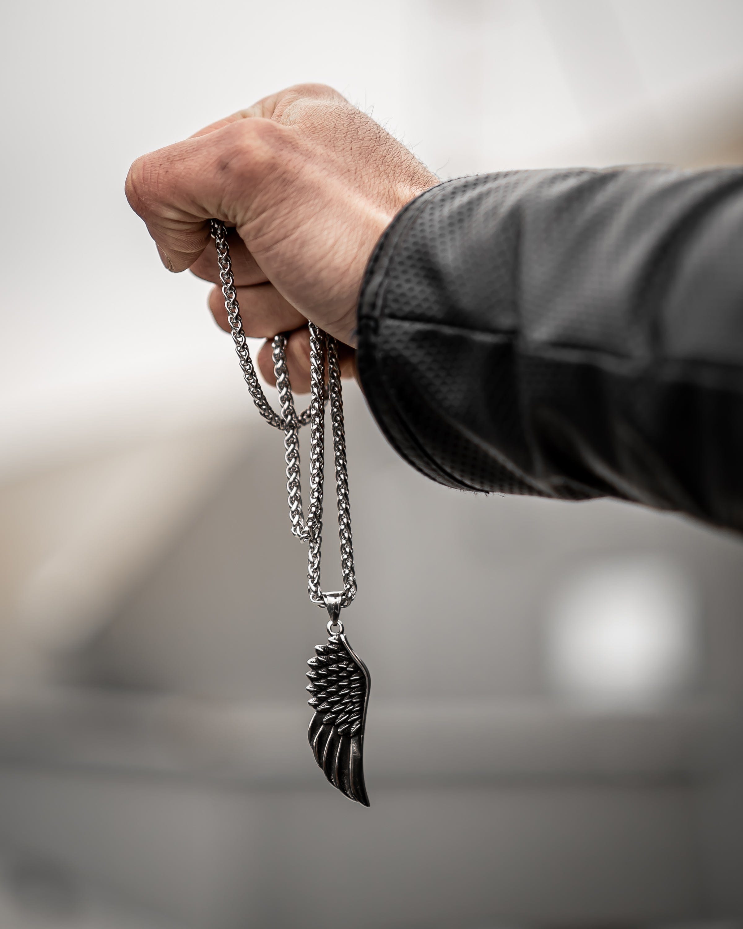 Muskarac drzi u ruci i detaljno pokazuje privezak i lanac muske ogrlice Freedom, HIRUSKI CELIK, srebrna boja, Najbolja cena i prodaja u Srbiji, model 6